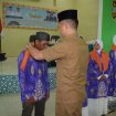 Bupati Gunung Mas Jaya S Monong sedang memasang kain tanda diberangkatkannya jemaah haji di aula Kemenag, Senin (13/5/2024).