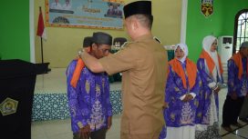 Bupati Gunung Mas Jaya S Monong sedang memasang kain tanda diberangkatkannya jemaah haji di aula Kemenag, Senin (13/5/2024).