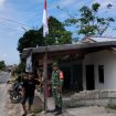 FOTO : Anggota TNI saat bersama warga memasang bendera merah putih.