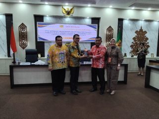 SERAHKAN : Pimpinan Bank Kalteng Cabang Kuala Kurun Empas S Umar saat menyerahkan alat rekam transaksi pajak ke Sekda Gumas, yang selanjutnya diserahkan ke para pelaku usaha, di ruang rapat lantai 1 kantor bupati setempat, Kamis, 4 Desember 2025.