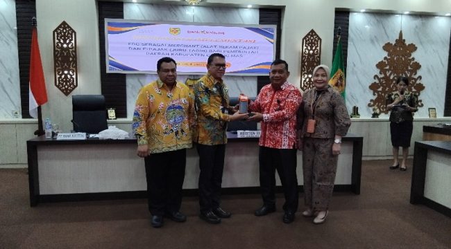 SERAHKAN : Pimpinan Bank Kalteng Cabang Kuala Kurun Empas S Umar saat menyerahkan alat rekam transaksi pajak ke Sekda Gumas, yang selanjutnya diserahkan ke para pelaku usaha, di ruang rapat lantai 1 kantor bupati setempat, Kamis, 4 Desember 2025.