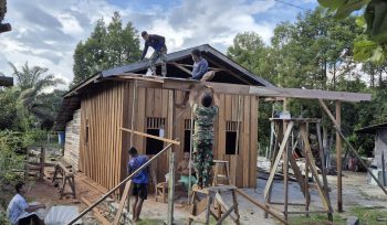 FOTO : Suasana pembangunan rumah dilakukan secara gotong royong dengan melibatkan personel TNI bersama masyarakat desa.