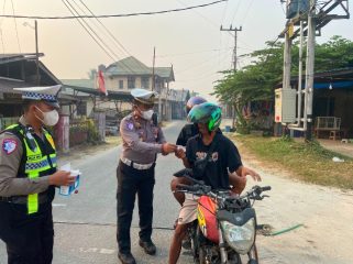 BAGIKAN : Kasat Lantas Polres Gumas Iptu Eko Erry Setiawan, S.H, M.H didampingi personel satlantas, saat membagikan masker kepada pengendara roda dua dan empat yang melintas, di Pos Lantas Taman Kota Kuala Kurun, Rabu, 26 Agustus 2026.